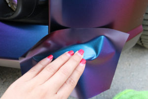 Applying vinyl wrap to damaged area with fingertips